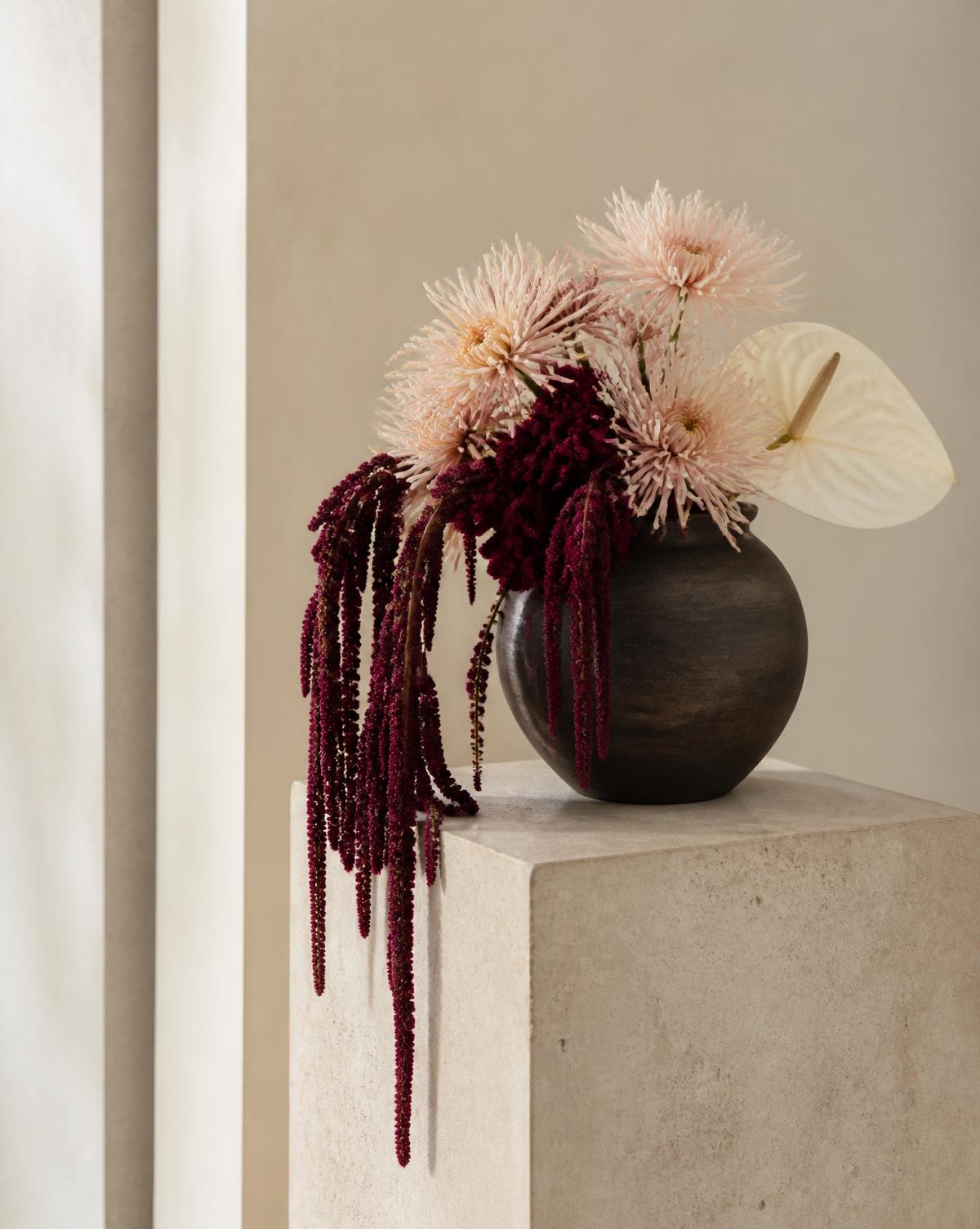 Burgundy and blush sculptural flowers in a dark handmade vessel